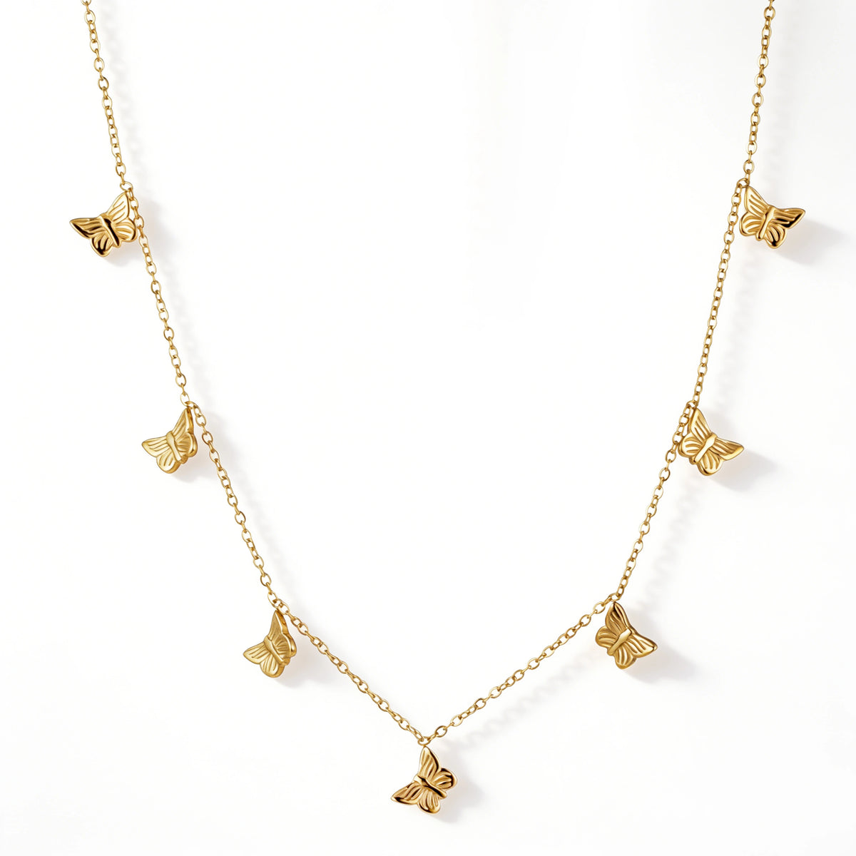 Gold necklace featuring multiple textured butterfly charms spaced along a fine chain, shown on a white background.