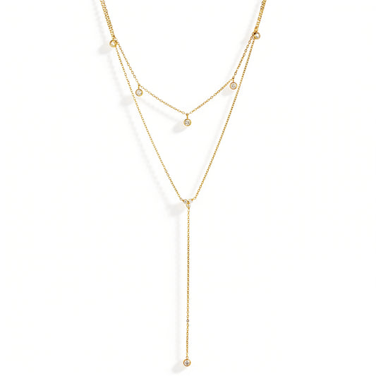 Gold necklace featuring layered fine chains, small round details and a long drop, shown on a white background.